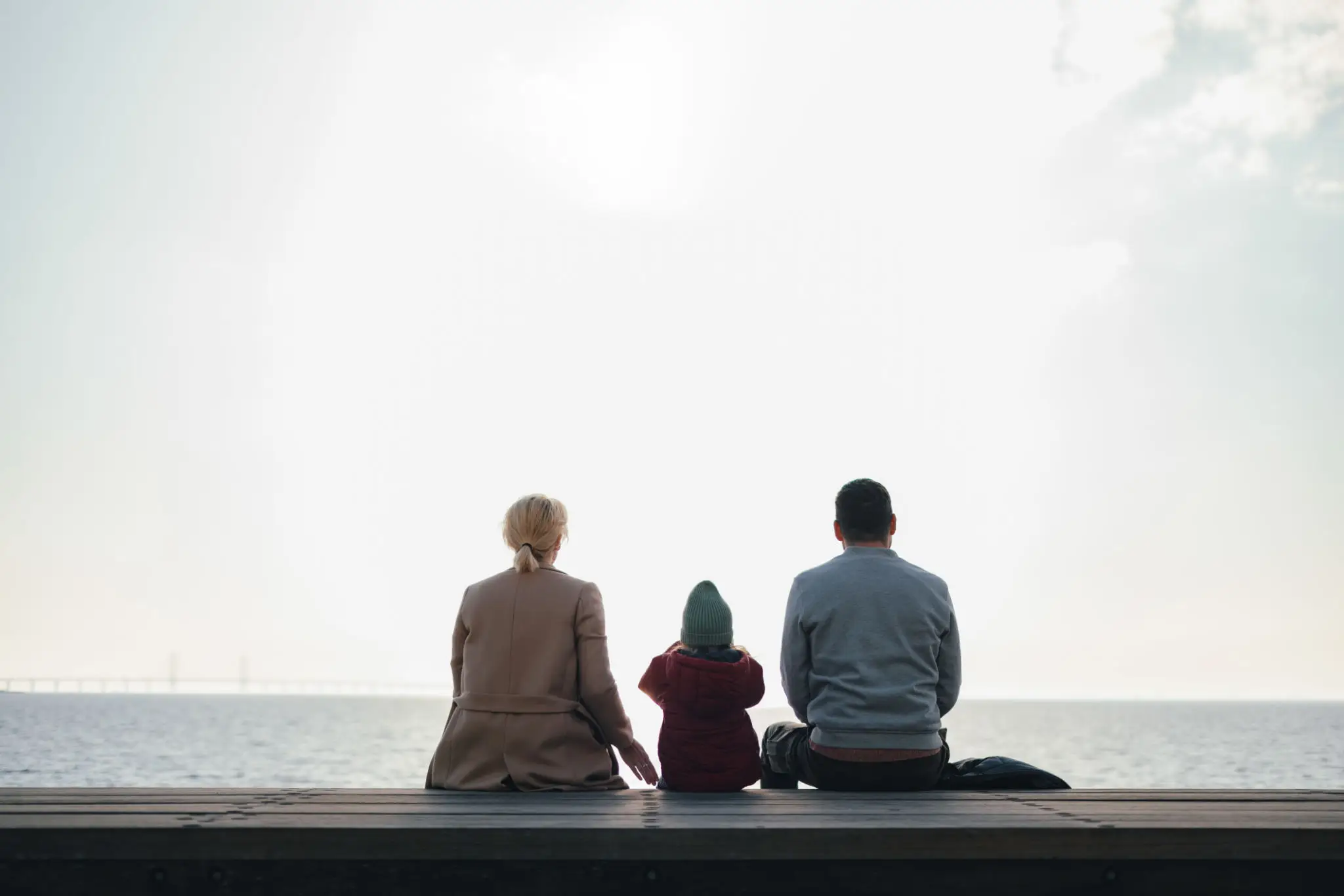 Three people sitting together, looking into the bright horizon.