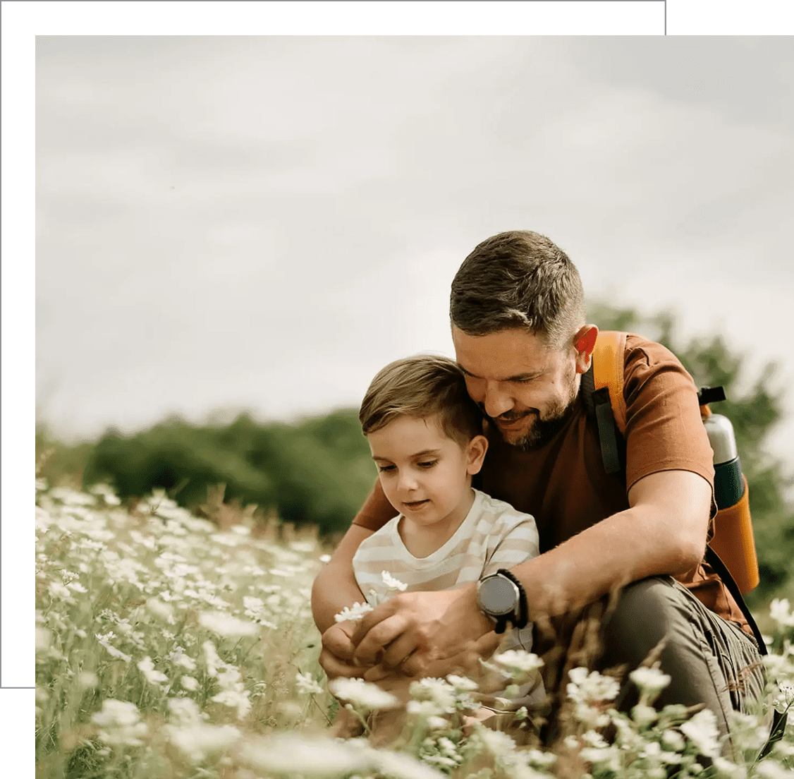 A father and son enjoying nature in a field of flowers.