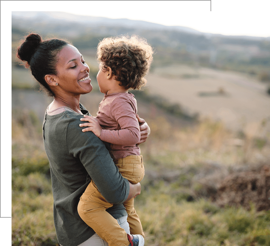 A mother holding her child outdoors, sharing a joyful moment.